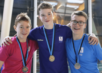 Three young divers sporting medals.