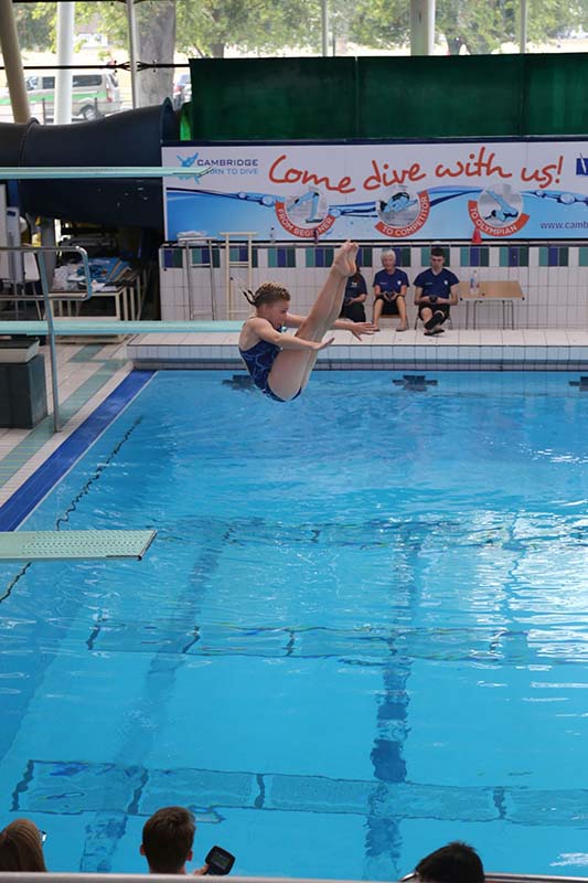 Child diving. She is in mid-air in pike position