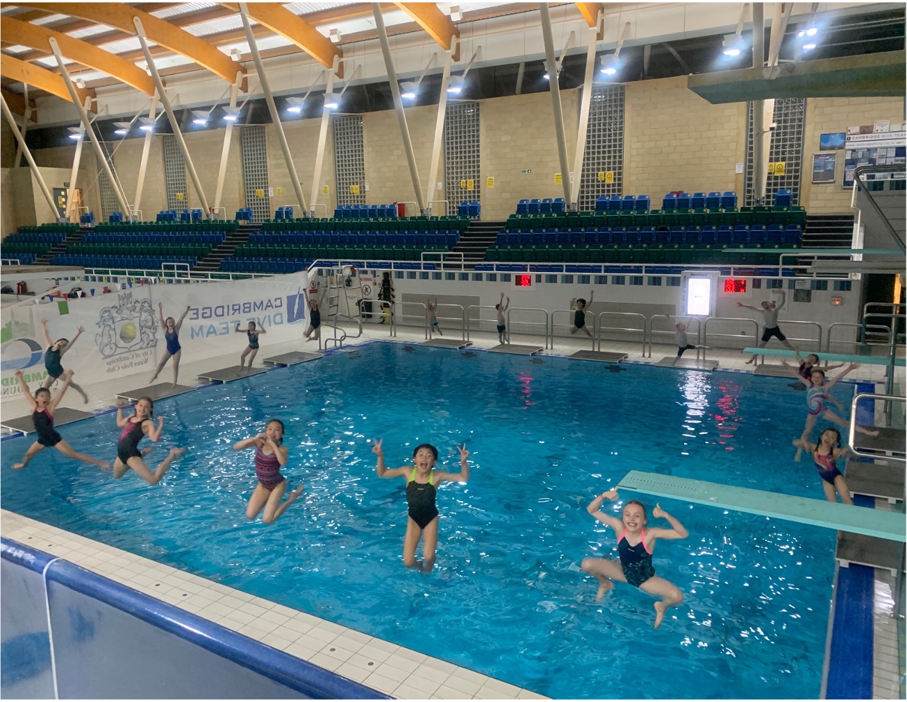 Five CDT divers in mid air as they jump backwards from poolside into the diving pool